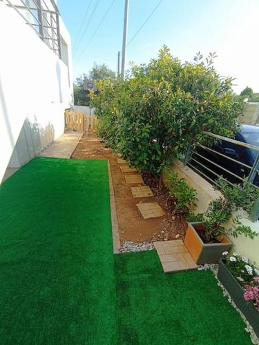 a garden with green grass on the side of a building at Alba - Open Plan Apartment in Artemida
