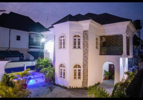 a large white house at night with lights at West End Mansion in Ikota