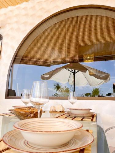 un tavolo con piatti e bicchieri da vino e un ombrello di Casa Heresa - große Terrasse mit Meerblick a Costa Calma
