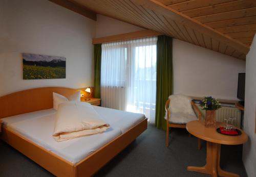 a bedroom with a bed and a table and a window at Alpenlodge Pfronten in Pfronten