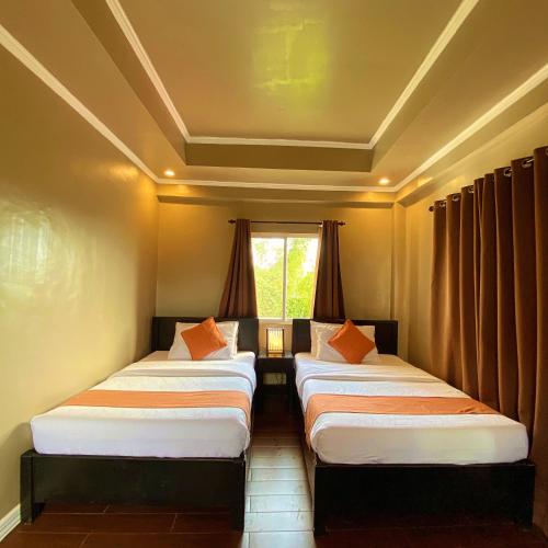 a row of three beds in a room with a window at Vela Terraces Hotel in Coron