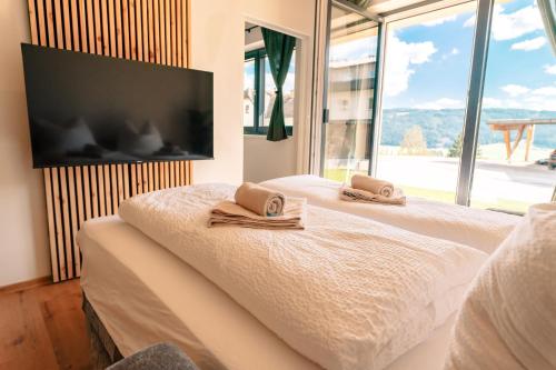 a bedroom with a bed with towels and a flat screen tv at Höhenweg Appartement & Ferienwohnung in Mariapfarr