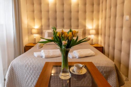 a vase of flowers on a table on a bed at APARTAMENTY VILLA PIGMALION - sauna, jacuzzi, parking, ogród in Kudowa-Zdrój