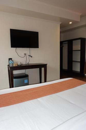 a bedroom with a bed with a television on the wall at Vela Terraces Hotel in Coron