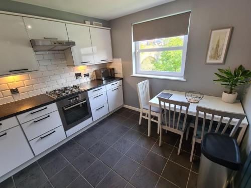 a kitchen with white cabinets and a table with chairs at Modern 2 Bed Flat with Parking in Aberdeen