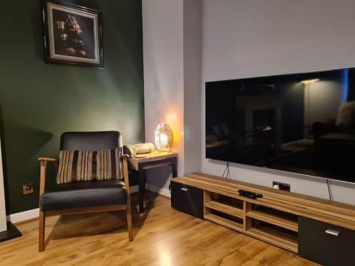 a living room with a chair and a large television at Modern 2 Bed Flat with Parking in Aberdeen