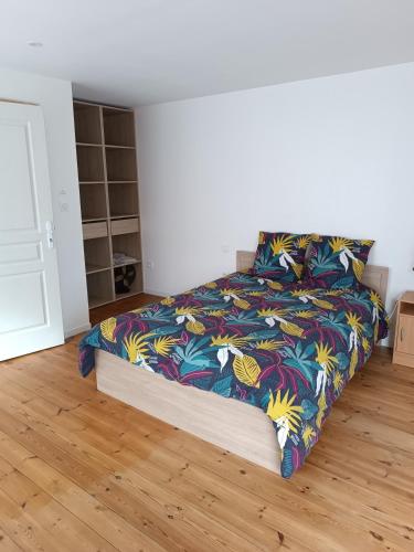 une chambre avec un lit avec une couette colorée dans l'établissement Au coin de la rue, à Saint-Vincent-Sterlanges