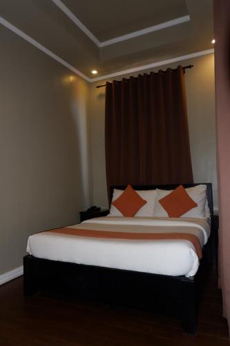 a bedroom with a bed with orange pillows at Vela Terraces Hotel in Coron