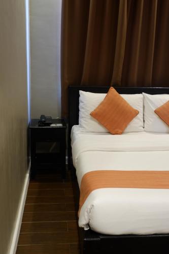 a hotel room with a bed with orange and white pillows at Vela Terraces Hotel in Coron