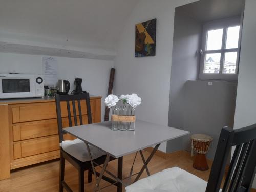 une cuisine avec une table avec un vase de fleurs dessus dans l'établissement Clos des jardinieres, à Mende