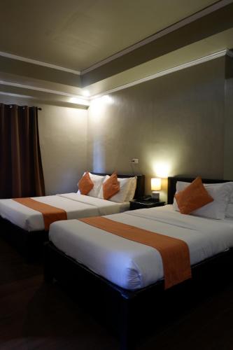 a hotel room with two beds with orange pillows at Vela Terraces Hotel in Coron