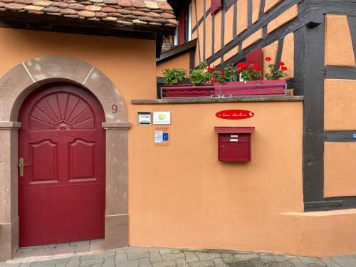 a building with a red door and two potted plants at La Cour des Amis in Vendenheim