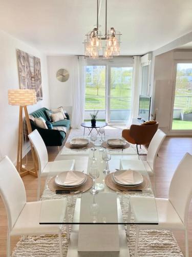 un salon avec une table en verre et des chaises dans l'établissement Le Domaine Réservé , parking et écrin de verdure, à Amiens