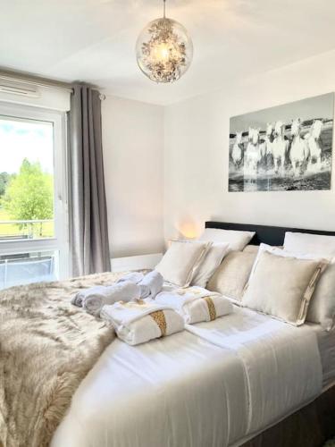 une chambre avec un grand lit blanc avec une fenêtre dans l'établissement Le Domaine Réservé , parking et écrin de verdure, à Amiens