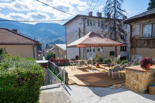 a patio with an umbrella and chairs on a wooden deck at Modern Studio Apartment in the Old Town in Sarajevo