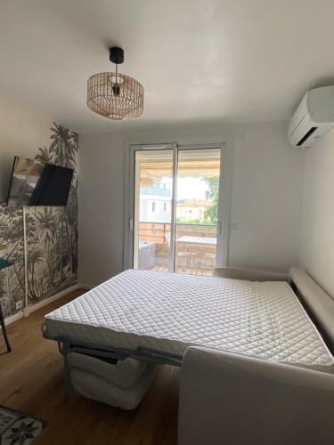 une chambre avec un lit blanc et une fenêtre dans l'établissement Studio 150 m de plage Golfe de Saint-Tropez, à Cavalaire-sur-Mer