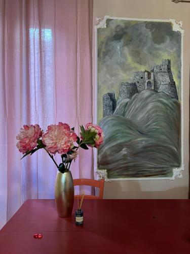 a vase with flowers on a table with a painting at Menhir Rooms in Campobasso