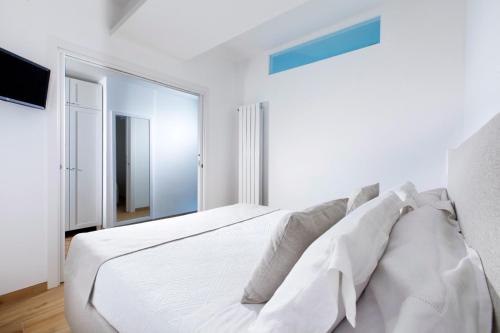 a white bedroom with a large white bed with pillows at Solymar Suite in Sorrento