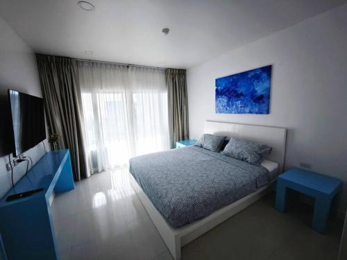 Un dormitorio con una cama con una mesa azul y un televisor. en Karon Beach Large 2 bedrooms & living room Seaview apartment, en Ka Rorn