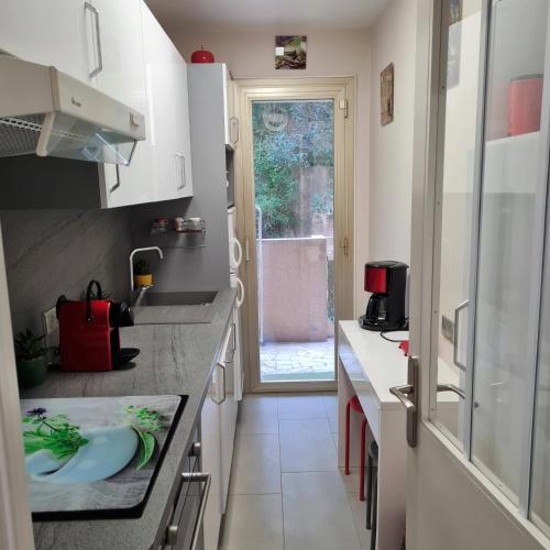 une petite cuisine avec un évier et une fenêtre dans l'établissement Charmant 2 pièces, traversant, clim, wifi, parking, à Cannes
