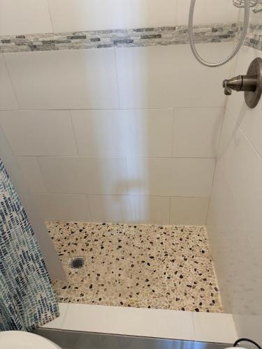 a bathroom with a shower with a tiled floor and a toilet at Aguada Beach Condos in Aguada
