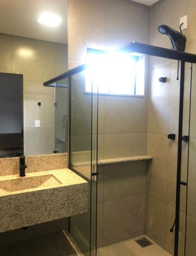 a bathroom with a glass shower with a mirror at ESCARPAS FLATS in Capitólio