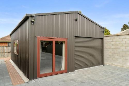 a gray garage with red doors and a building at The Iron Gate Family Hideaway - Pet Friendly in Cromwell