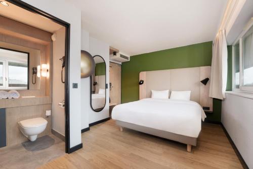 a bedroom with a white bed and a green wall at Campanile Prime Paris 19 - La Villette in Paris