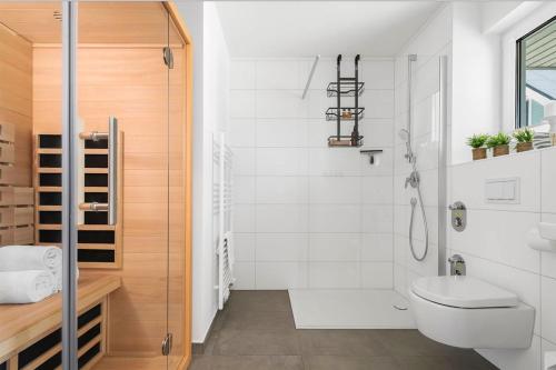 a white bathroom with a toilet and a shower at Maltes-Ostseekoje Parken frei vorm Haus, 500m zum Strand,Infrarotsauna,Magenta TV mit Netflix ,Disney TVund Rtl plus, Kaminofen im Wohnzimmer,ab Oktober Brennholz gratis Fahrradschuppen,Mückenschutz in Olpenitz