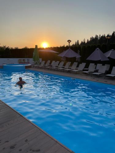 a man swimming in a swimming pool at sunset at СПА-Готель "RESPECT" in Skhidnitsa