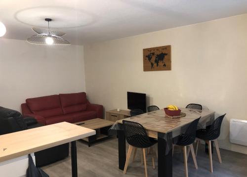 un salon avec une table et un canapé rouge dans l'établissement Appartement T3, à Bagnères-de-Bigorre