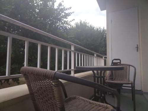 a porch with two chairs and a table on a balcony at Appartement familial face à un square arboré in Enghien-les-Bains