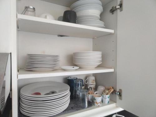 a cupboard with plates and dishes in it at Appartement familial face à un square arboré in Enghien-les-Bains