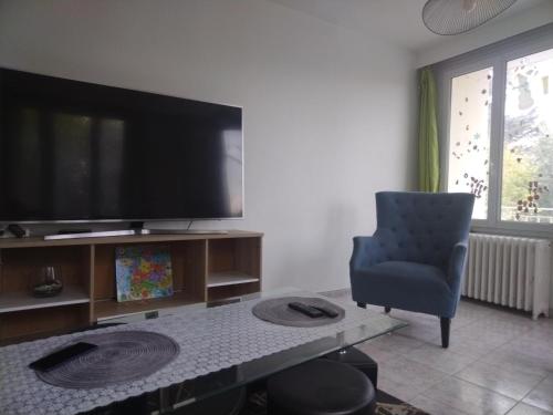a living room with a flat screen tv and a chair at Appartement familial face à un square arboré in Enghien-les-Bains