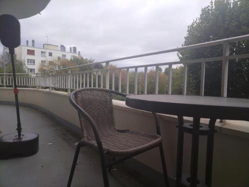 a table and a chair on a balcony at Appartement familial face à un square arboré in Enghien-les-Bains