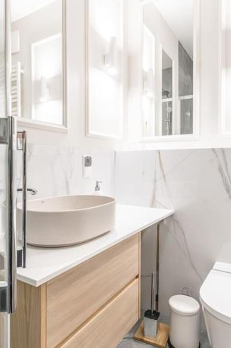 a white bathroom with a sink and a toilet at Old Town Vibes Premium AON Apartment in Gdańsk