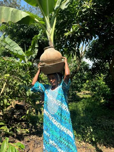 a girl in a blue dress carrying a basket on her head at Kibale Cultural Homestay in Fort Portal
