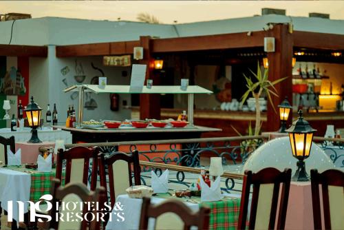 a restaurant with a table and chairs and a kitchen at MG Alexander The Great Hotel in Marsa Alam City