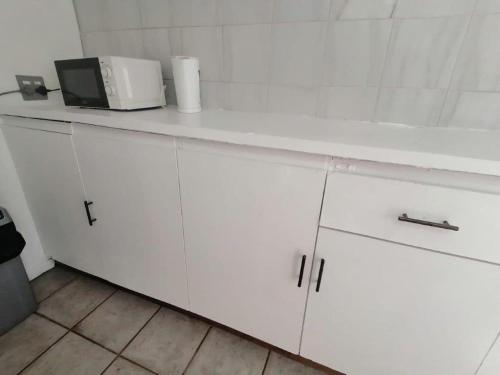 a kitchen counter with white cabinets and a microwave at Kings Lodge Hotel in Hogsback