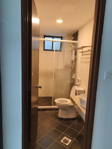 a bathroom with a toilet and a glass shower at Marina Heights Apartment in Lumut