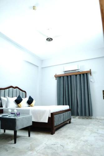 a bedroom with a bed and a couch and a table at Serenity Lodge Guest House in Kalar Goth