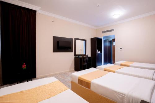 a hotel room with three beds and a flat screen tv at فندق سيف بلص 2 من اورفانا in Makkah