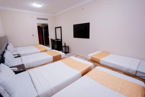 a room with four beds and a flat screen tv at فندق سيف بلص 2 من اورفانا in Makkah