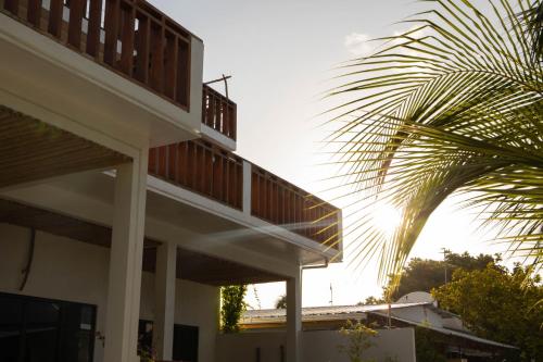a building with a balcony and a palm tree at Kudhi Boli Beach House in Thulusdhoo