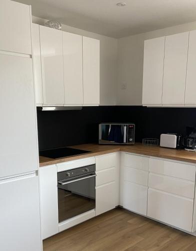 une cuisine avec des armoires blanches et un micro-ondes dans l'établissement Le Spot, appartement cosy à 1mn de la mer, Saint Aubin sur Mer, à Saint-Aubin-sur-Mer