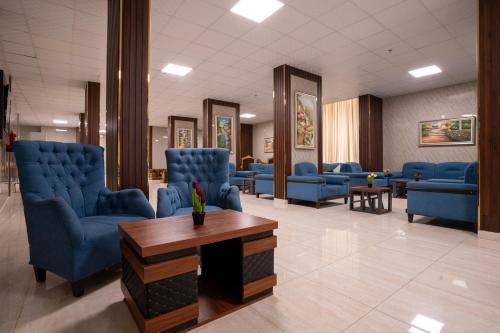 a waiting room with blue chairs and a table at فندق سيف بلص 2 من اورفانا in Makkah