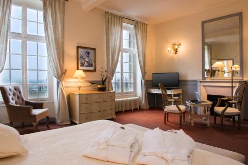 Dormitorio con cama, escritorio y TV en Hôtel Château de l'Hermitage en Pontoise