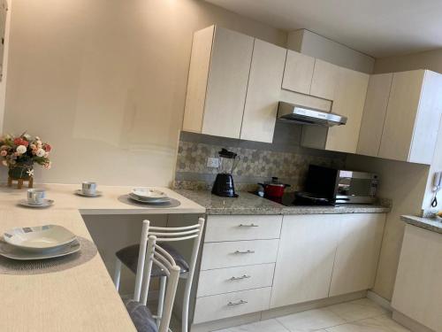 a kitchen with white cabinets and a counter with stools at Casa Centro Histórico Cuenca in Cuenca
