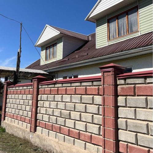 a brick retaining wall in front of a house at Ethno homestay in Teploklyuchinskoye