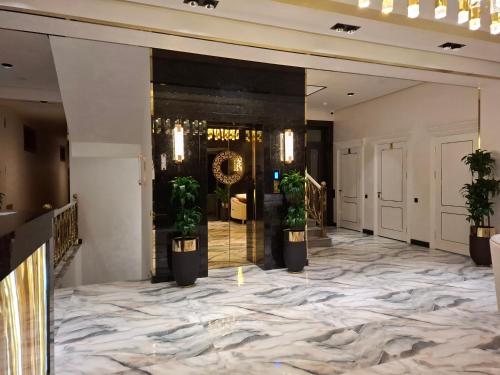 a lobby with a marble floor and potted plants at My Status Hotel in Tashkent